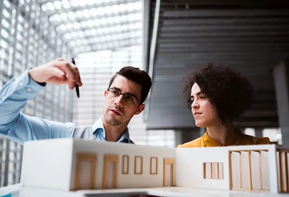 young-architects-with-model-of-a-house-standing-in